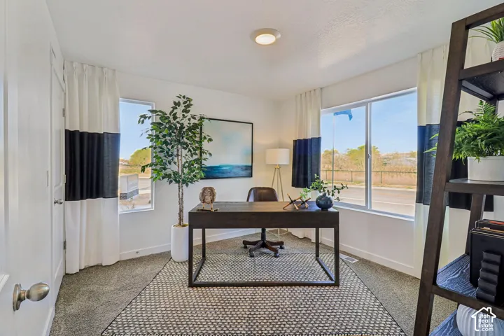 Recessed ceiling lighting, two large windows, light gray carpet, and white walls