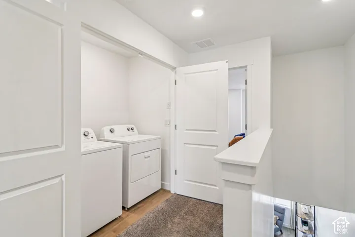 Laundry area with a washer and dryer, recessed lighting, and wood-finish flooring