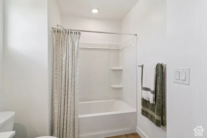 Tub and shower combination with an integrated storage niche, recessed ceiling light, and wall-mounted towel bar