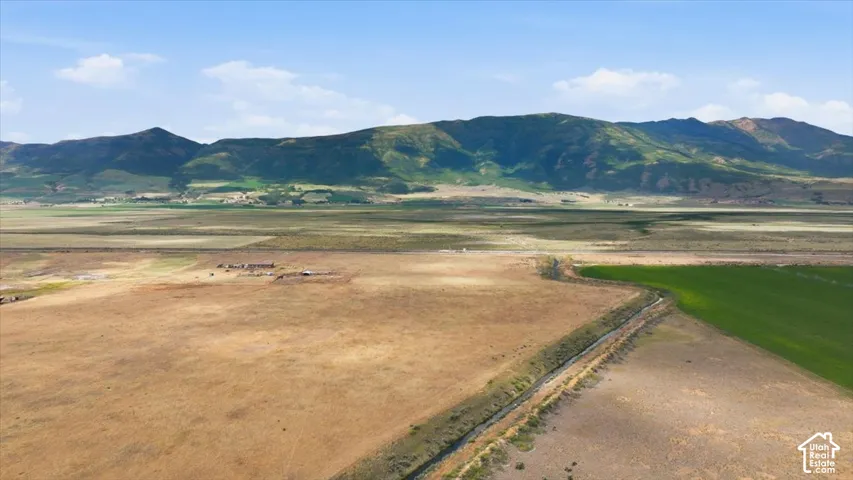 Expansive open land featuring a water channel, agricultural fields, and distant mountains