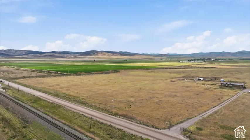 Expansive property featuring a single-story residence and outbuildings, with a gravel driveway and open fields