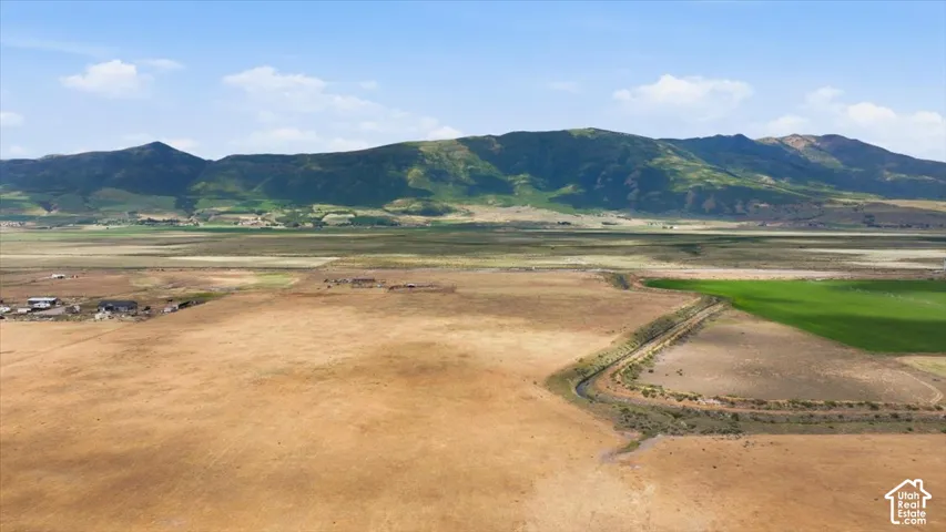 Expansive land parcel featuring open terrain, a defined water channel, and distant mountainous scenery
