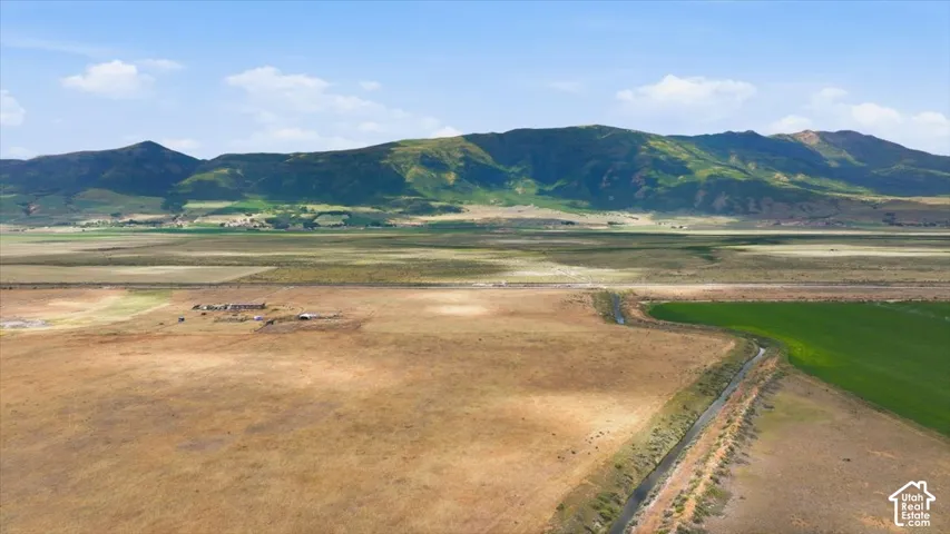 Expansive rural landscape featuring a water channel, agricultural fields, and distant mountains