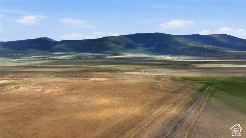Expansive open land with distant mountains under a blue sky