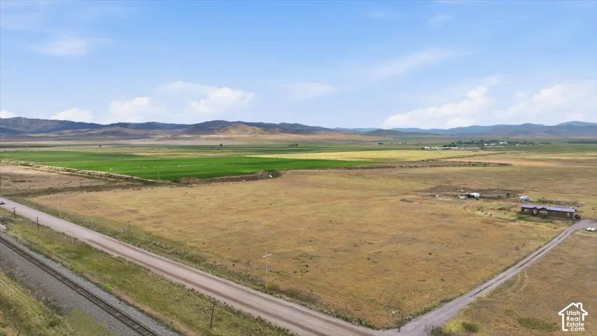 Expansive parcel featuring a single-story residence with a brown roof, multiple outbuildings, and a gravel drive