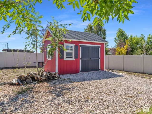 Red detached shed with a black shingle roof, black shutters, and double entry doors