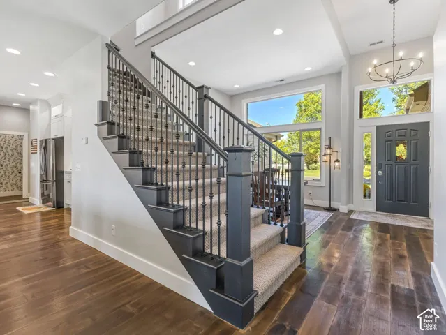 Hardwood-finish flooring, staircase with carpeted treads and wrought iron spindles, transom window over the entry door, and large picture windows