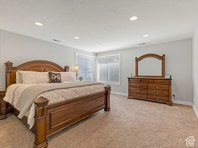 Recessed lighting illuminates a carpeted room with light gray walls and white trim