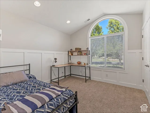 Arched window with blinds, recessed lighting, vaulted ceiling, board and batten wall detailing, and carpet flooring