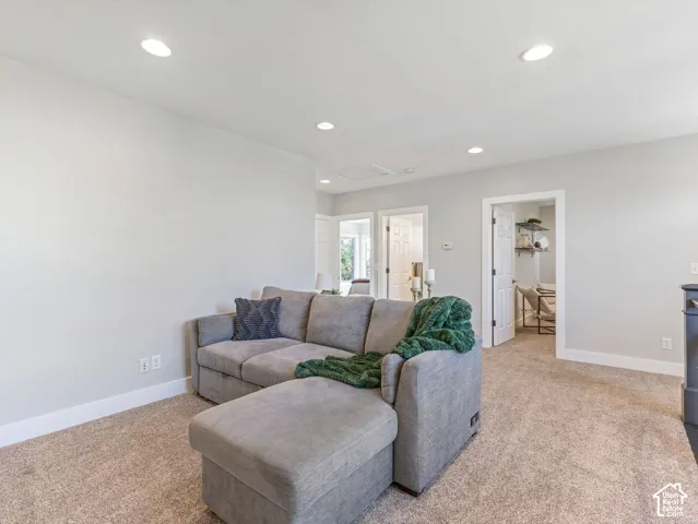 Recessed lighting, light-toned walls, and neutral carpet flooring