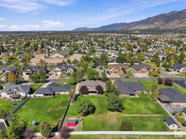 Expansive neighborhood featuring residential properties with manicured lawns, mature trees, and mountainous topography