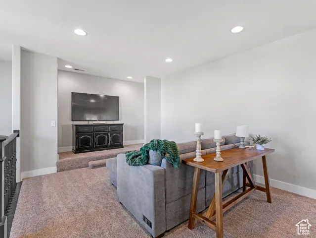 Recessed ceiling lighting illuminates a dedicated media area with a raised platform, featuring a built-in media console