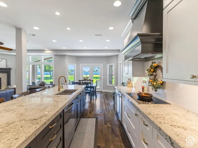 Open-concept kitchen featuring an expansive island with a built-in sink, granite countertops, and wood-finish flooring