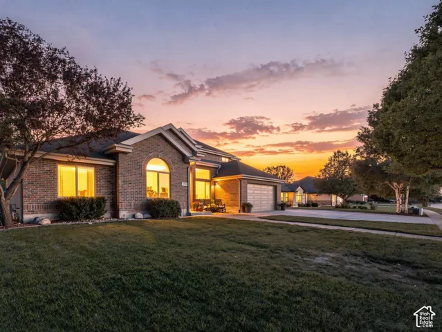 Brick exterior with arched window accent, attached two-car garage, and established landscaping