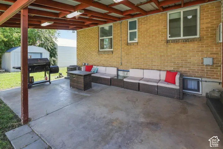 Covered patio with a concrete surface, exposed brick exterior, and multiple windows