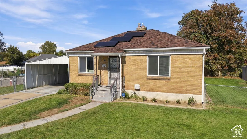 Brick-clad exterior with a covered carport, solar panels, and a concrete driveway