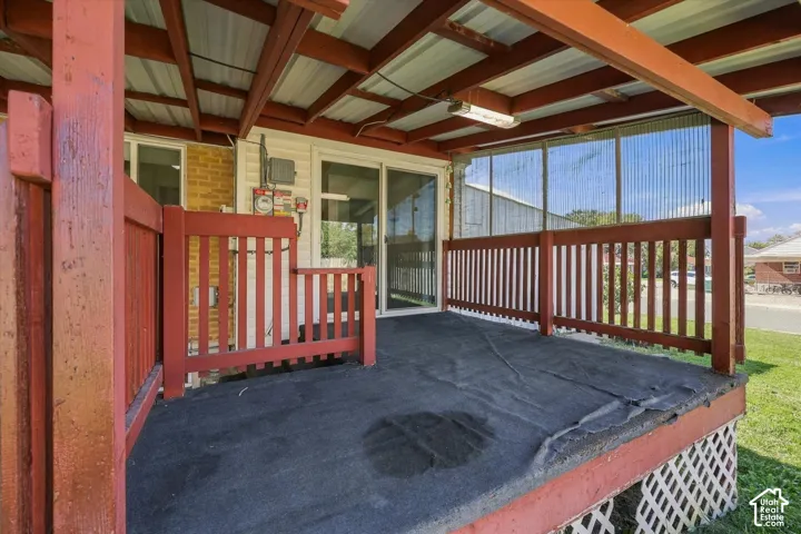 Covered deck with red-stained wood railing and white lattice skirting