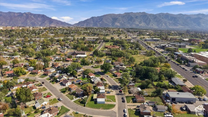 Residential neighborhood with varied rooflines and mature trees, surrounded by mountainous terrain
