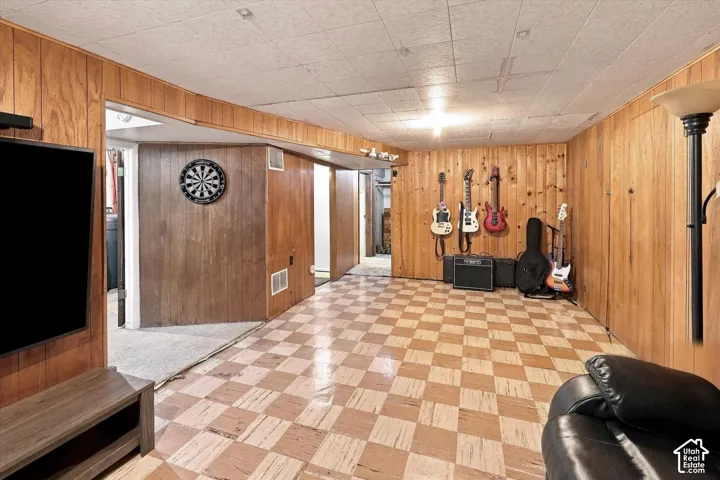 Wood-paneled walls, checkered flooring, and drop ceiling panels create a distinct aesthetic