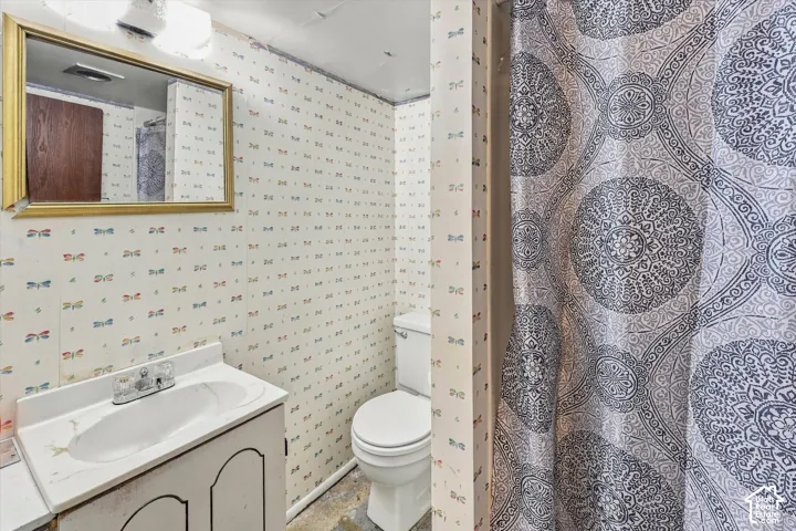 White vanity with integrated sink, gold-framed mirror, and toilet