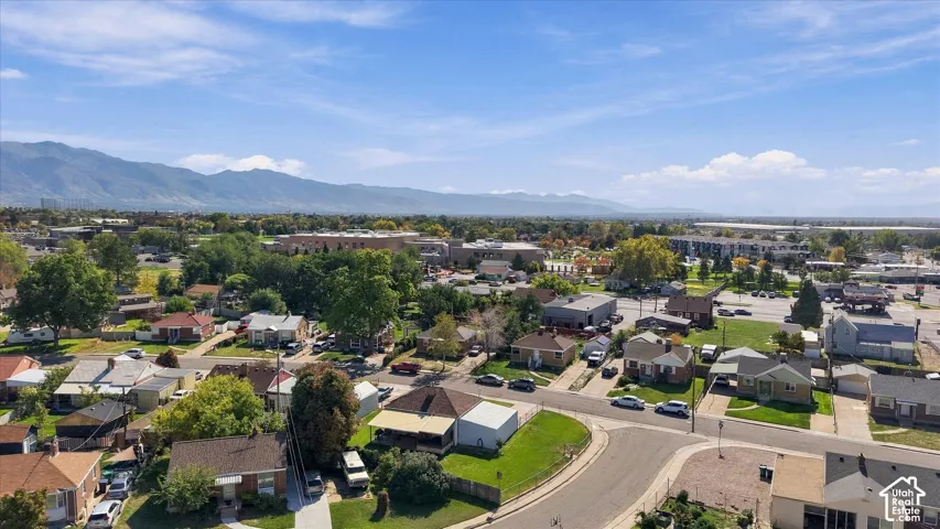 Residential neighborhood with tree-lined streets, expansive mountain backdrop, and commercial properties in the distance