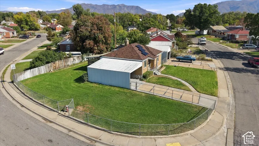 Corner lot property featuring a brick exterior, covered carport, solar panels, and a chain-link fence enclosing the front yard