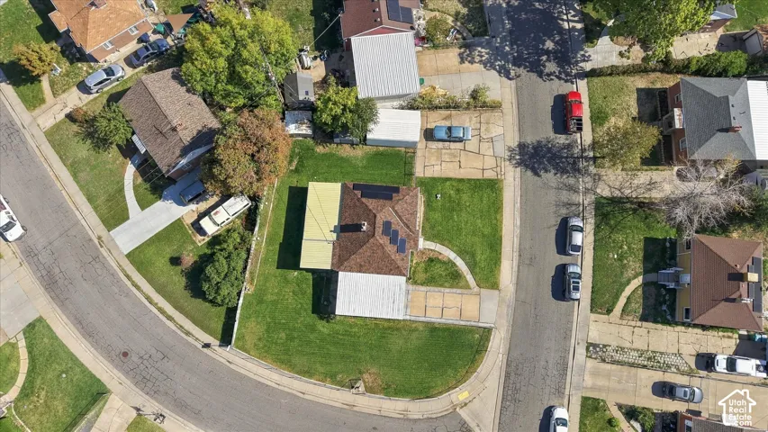 Pitched roof residence with solar panels, green lawn, and concrete driveway