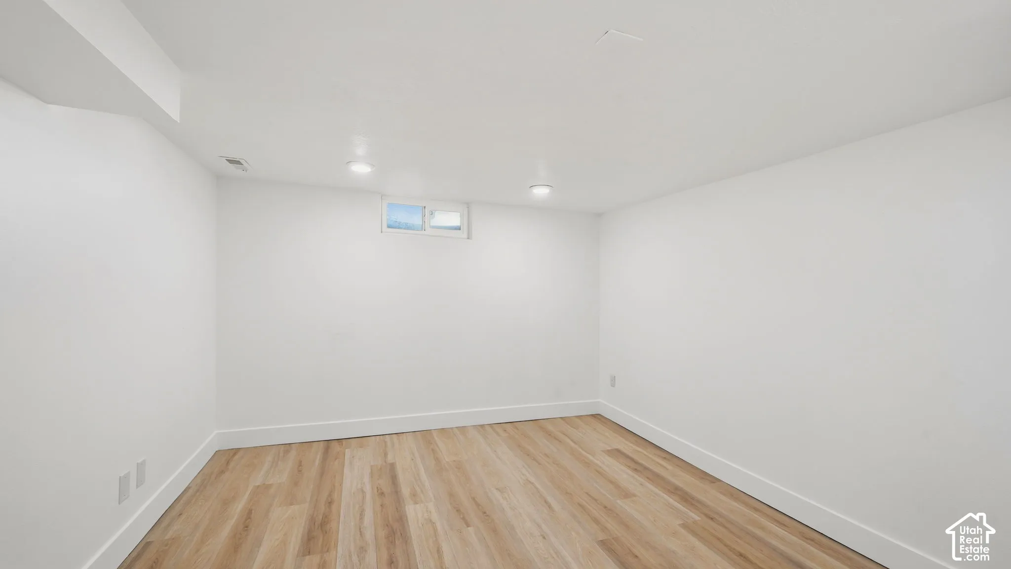 Recessed lighting, light wood-finish flooring, white painted walls, and a small transom window