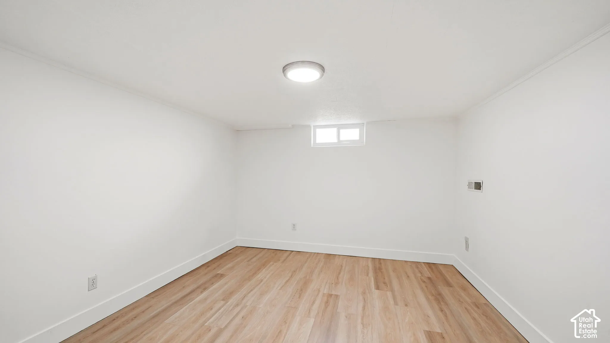 Light wood-finish flooring with white baseboards and walls