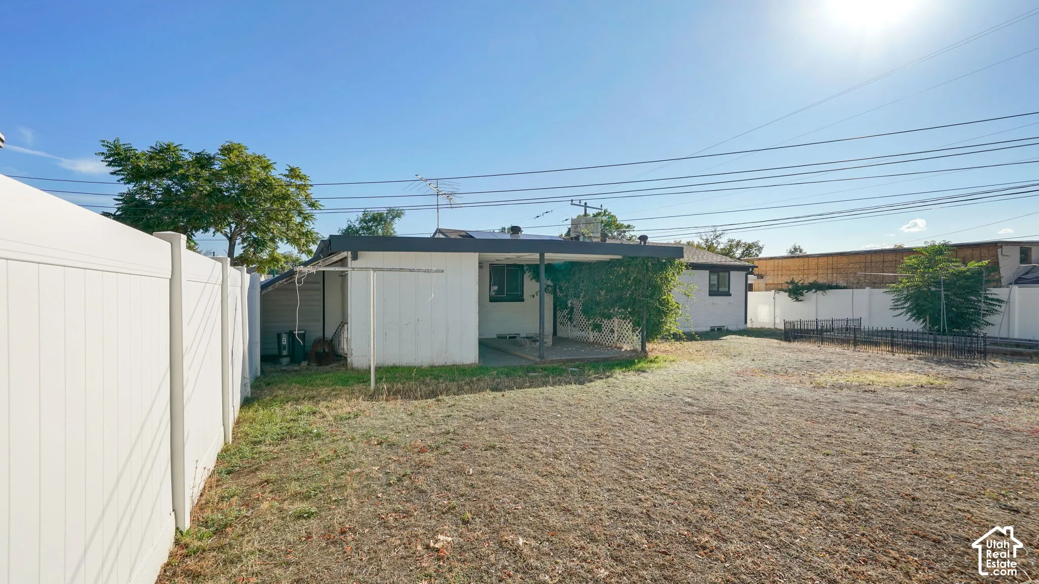 Expansive fenced yard with a covered patio area and mature trees