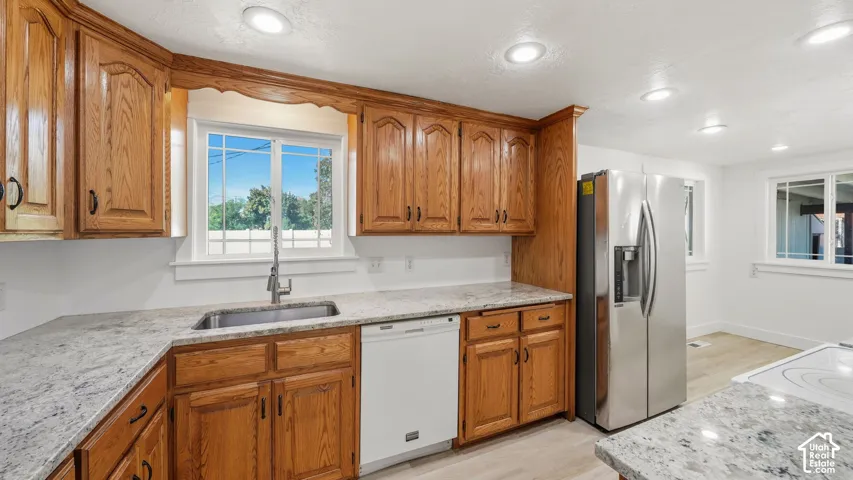 Kitchen featuring wood cabinetry, light-toned granite countertops, a stainless steel side-by-side refrigerator, and recessed lighting