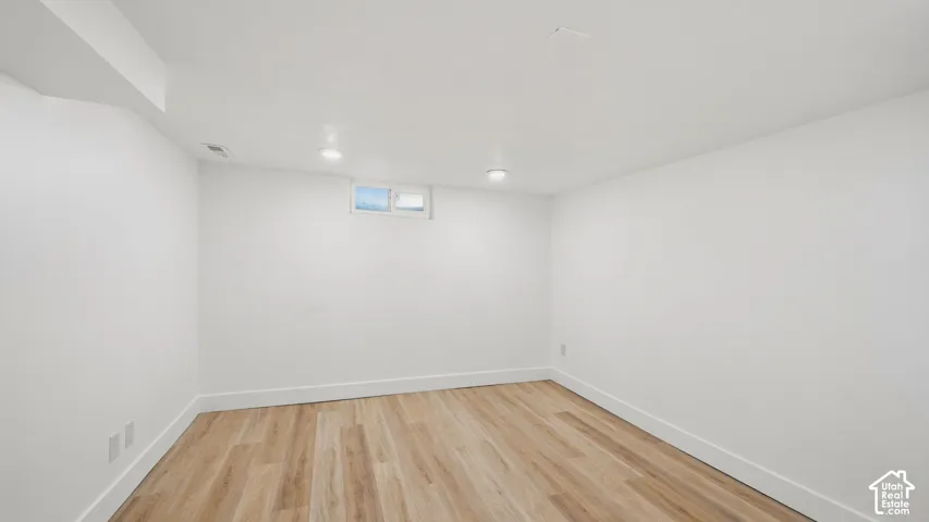 Recessed lighting, light wood-finish flooring, white painted walls, and a small transom window
