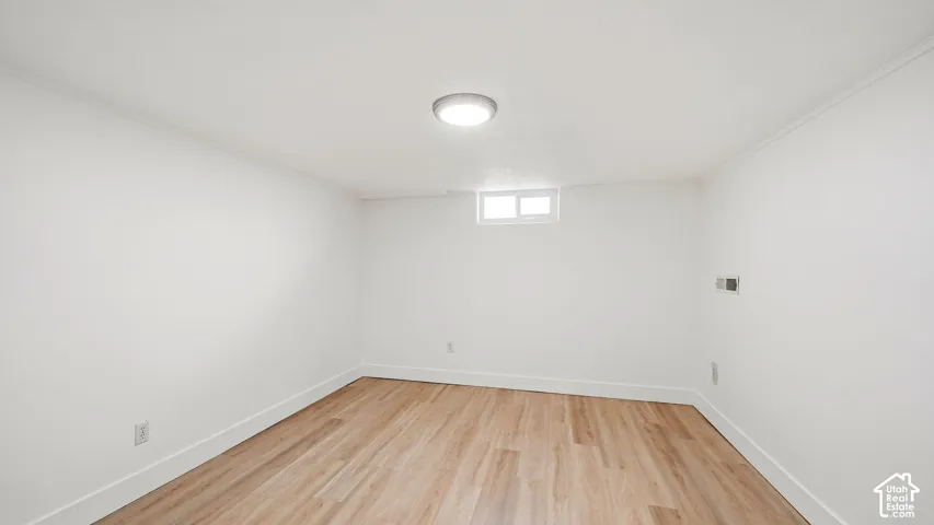 Light wood-finish flooring with white baseboards and walls
