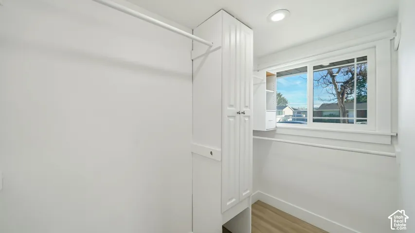 Built-in cabinetry, window with white trim, recessed ceiling light, wood-finish flooring, and white walls