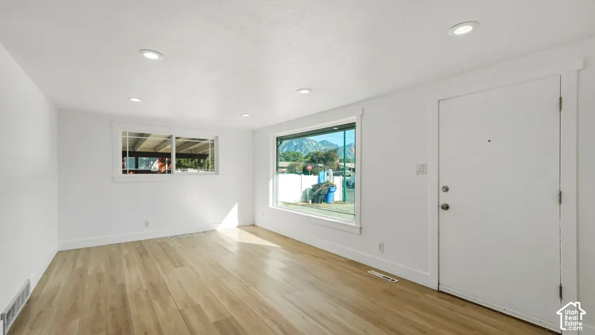 Recessed lighting illuminates wood-finish flooring in this room with multiple windows