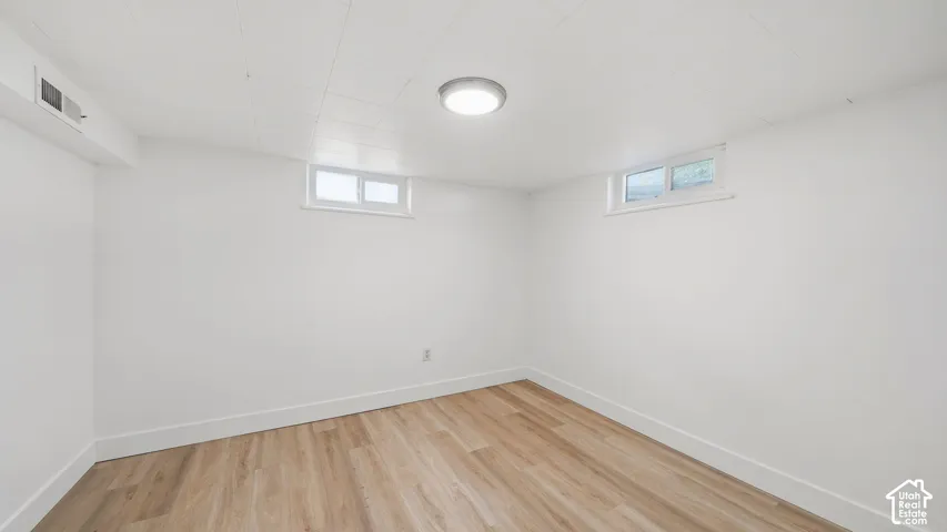 Recessed lighting, wood-finish flooring, white walls, and a visible air vent