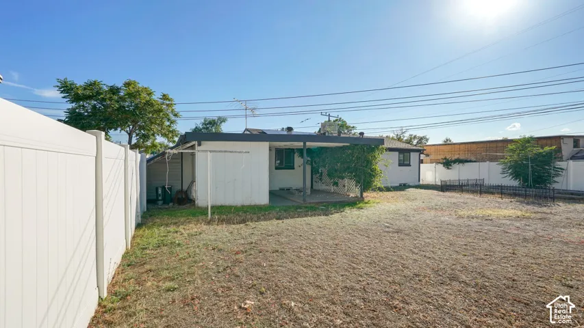 Expansive fenced yard with a covered patio area and mature trees