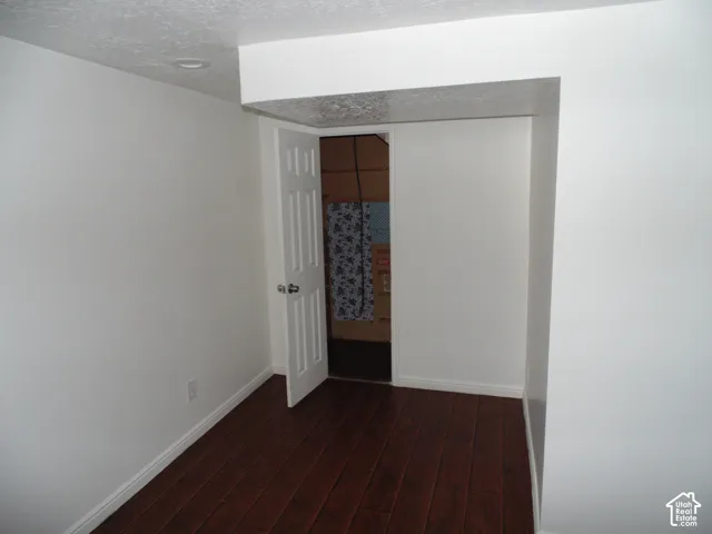 White paneled interior door, dark wood-finish flooring, recessed ceiling lighting, and crisp white walls