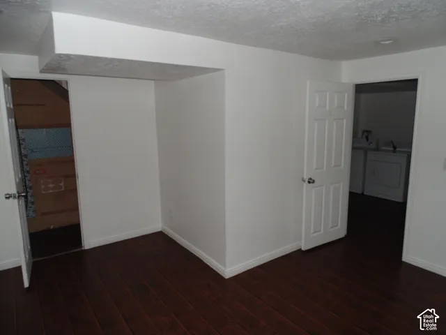 Wood-finish flooring with white baseboards, white walls, and white paneled interior doors