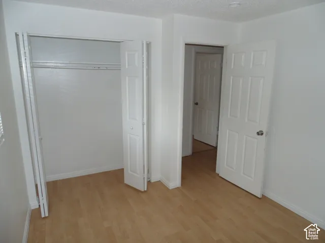 Wood-finish flooring, white walls, bi-fold closet doors, white interior doors, and overhead lighting
