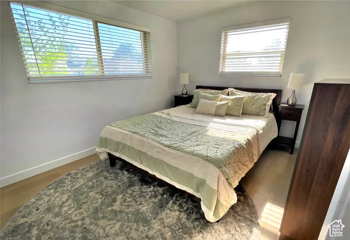 Light wood-finish flooring, white walls, and a large window with horizontal blinds
