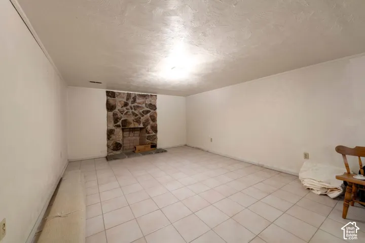 Spacious room featuring a stone-clad fireplace and tile flooring