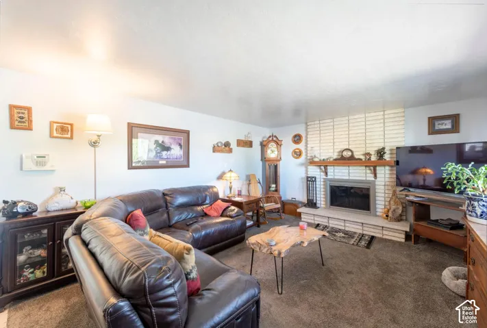 White brick fireplace with a wood mantle and hearth, recessed firebox, and carpeted flooring