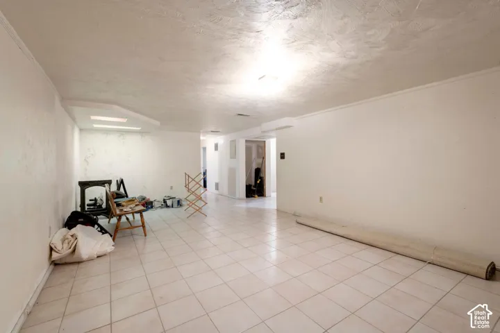 Spacious room featuring tile flooring, white walls, and a textured ceiling