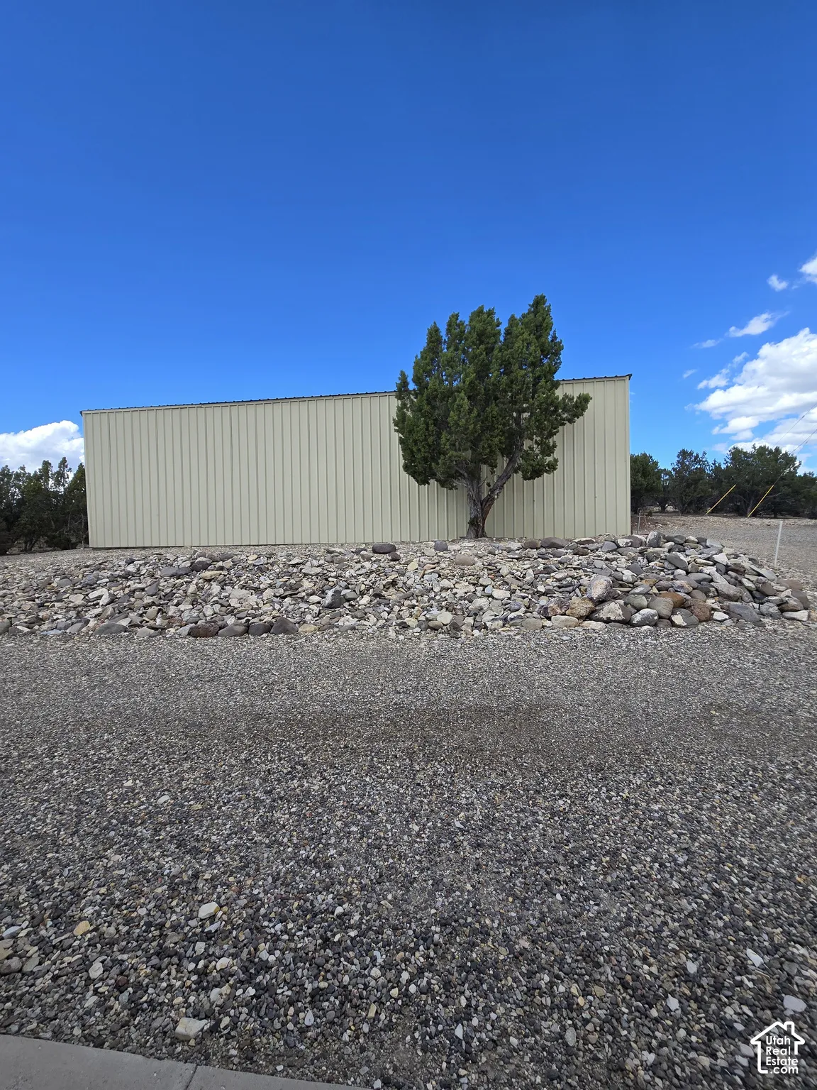 Metal-sided structure with a gravel foreground and natural rock landscaping
