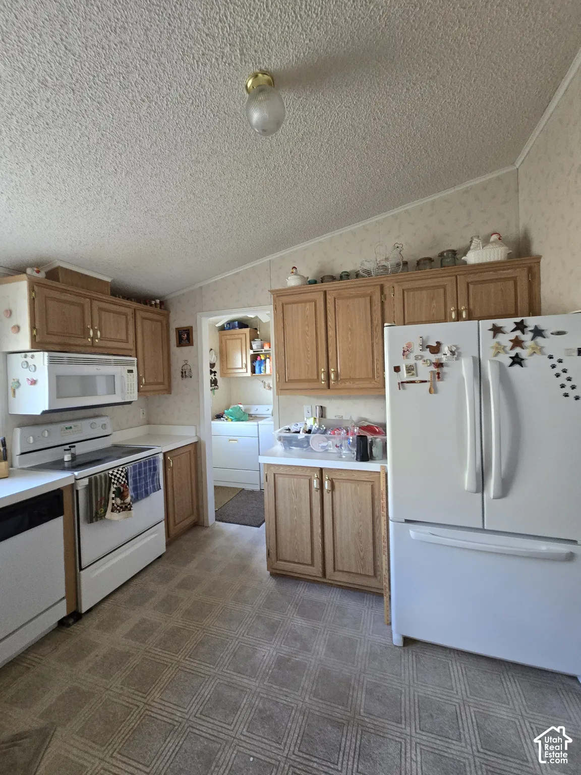 Kitchen featuring wood-finish cabinetry, white countertops, and white appliances