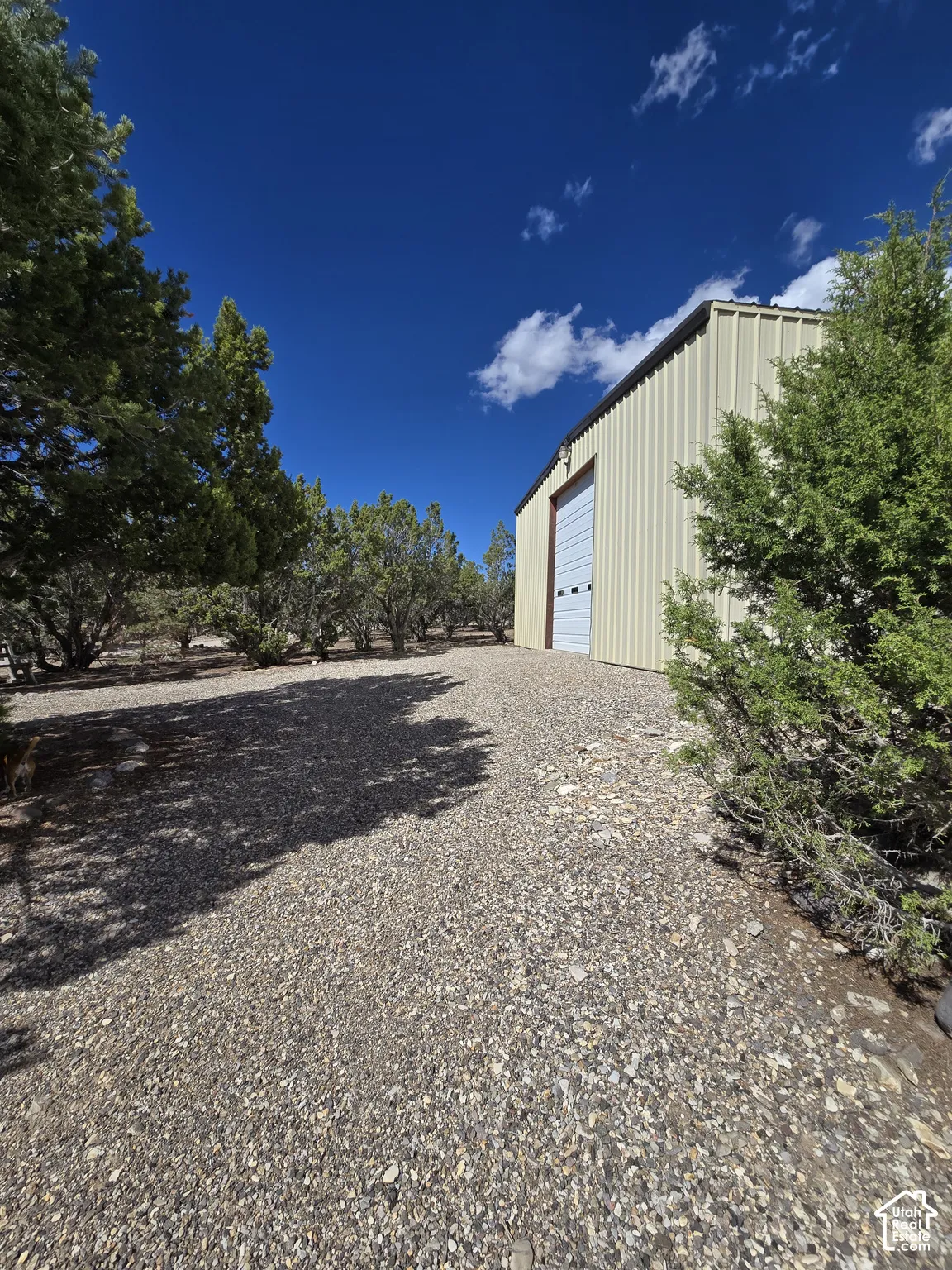 Corrugated metal exterior with a roll-up garage door, set on a gravel surface