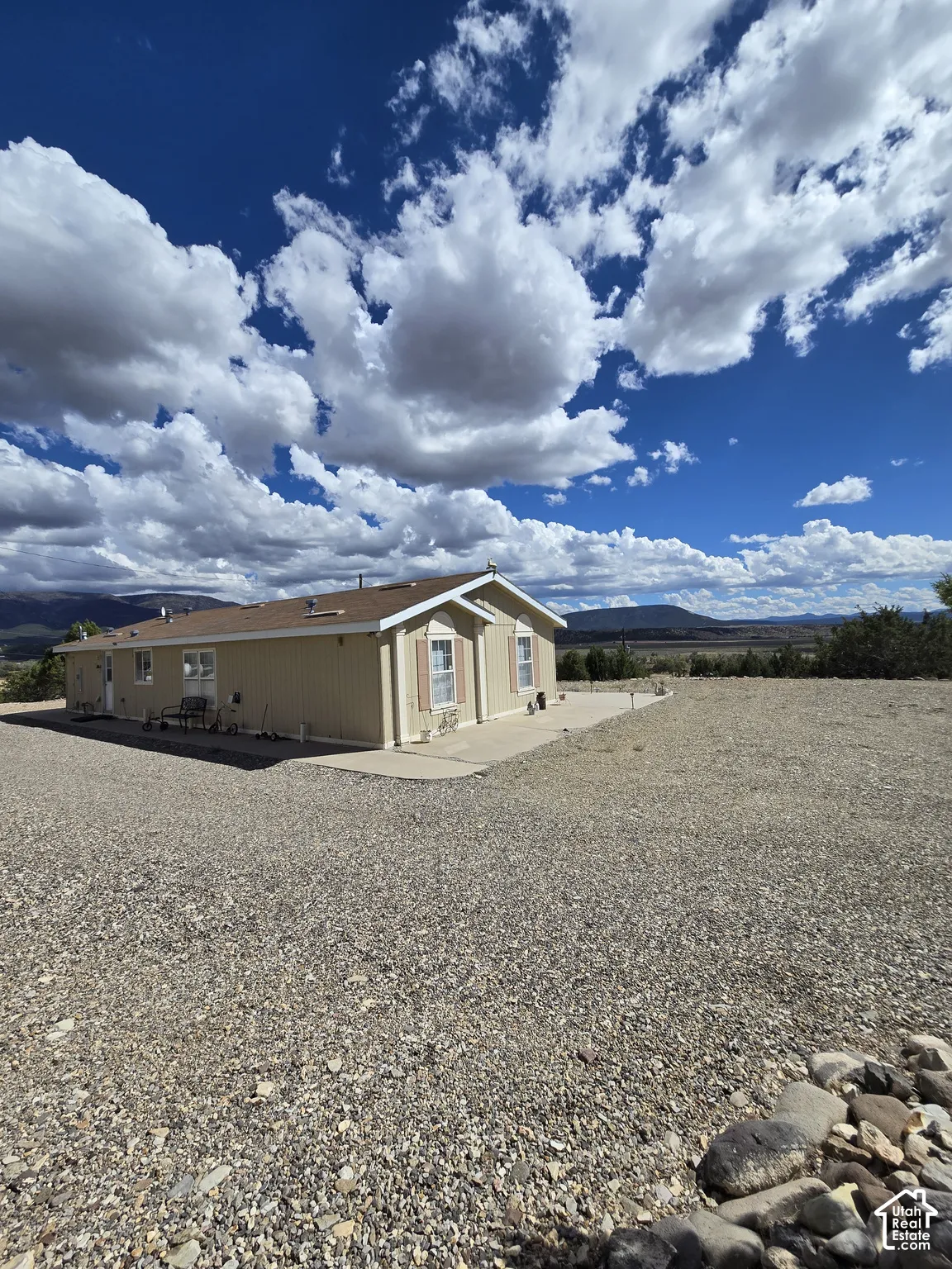 Single-story exterior with light-colored siding, contrasting roof, and a gravel-covered lot