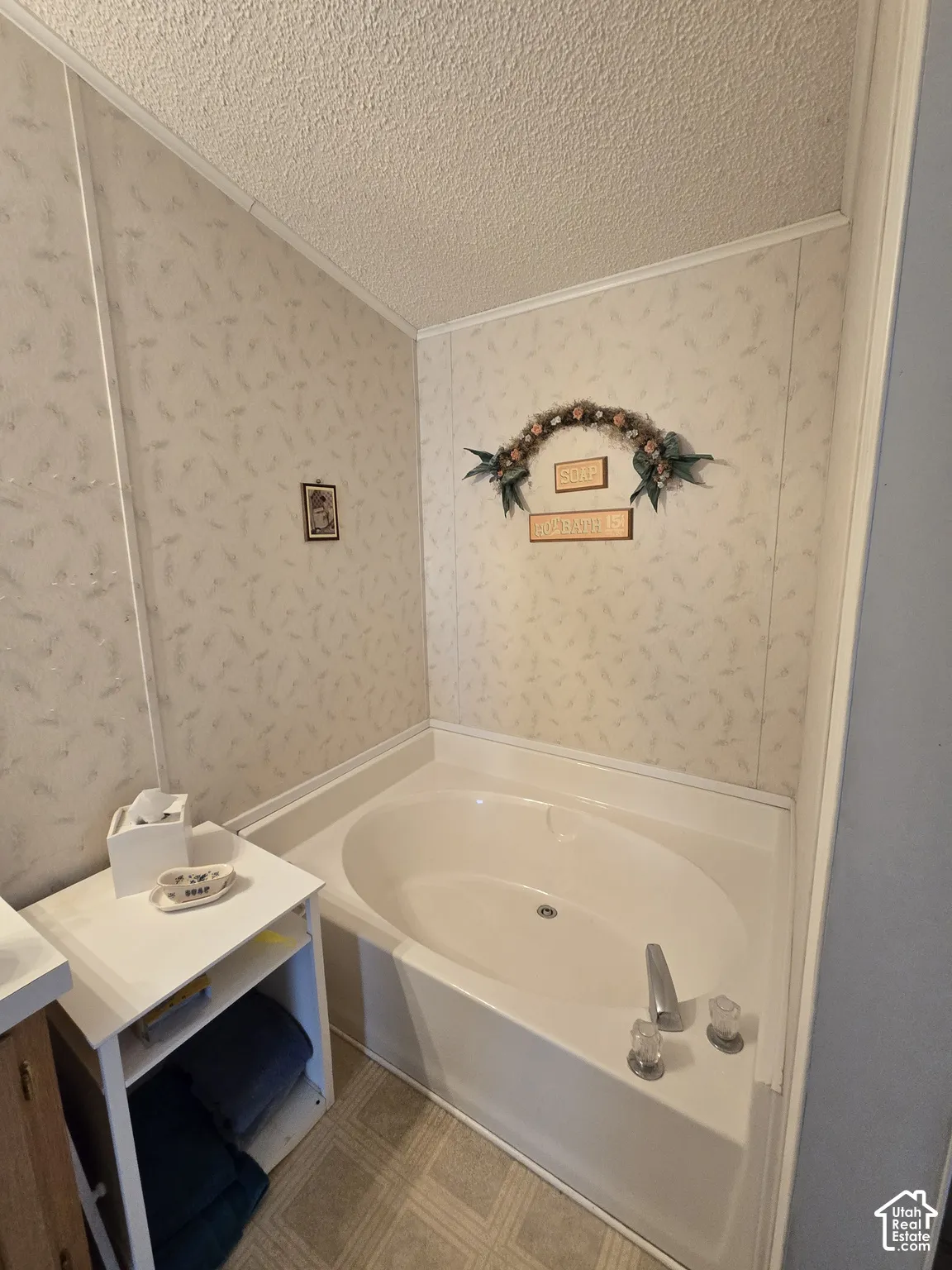Built-in corner soaking tub with chrome fixtures and light-colored patterned wall paneling
