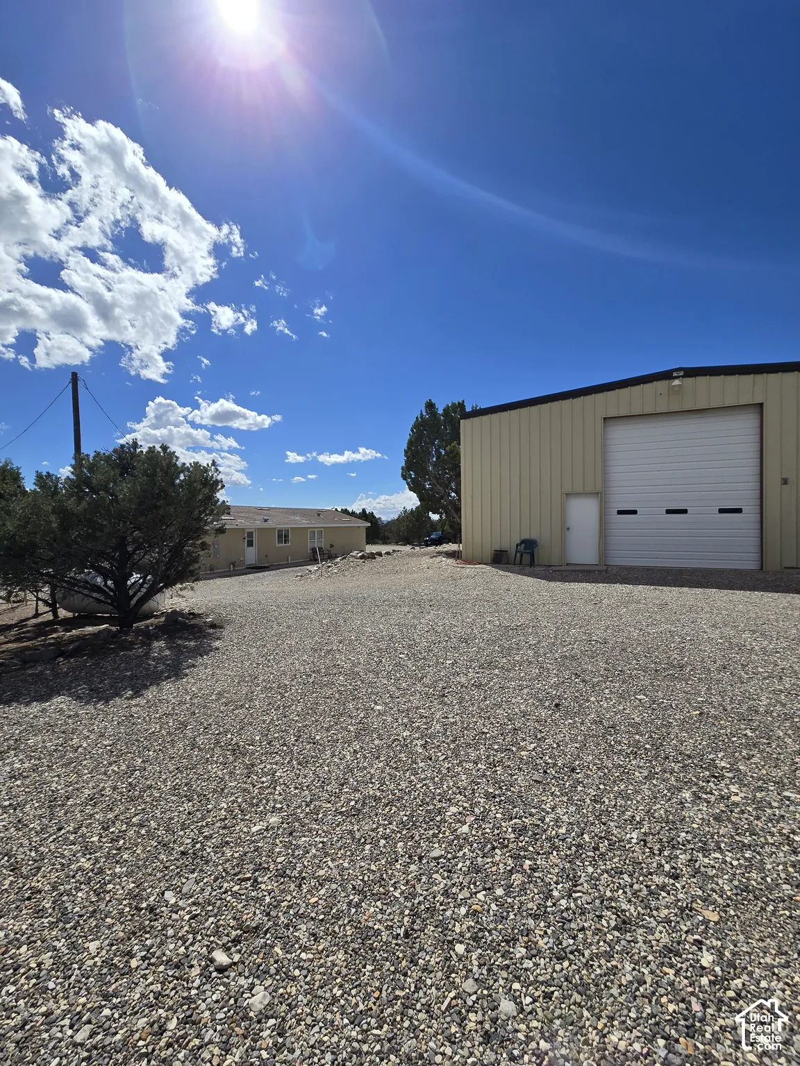 Gravel lot featuring a large metal-sided building with a roll-up door and a separate entry door